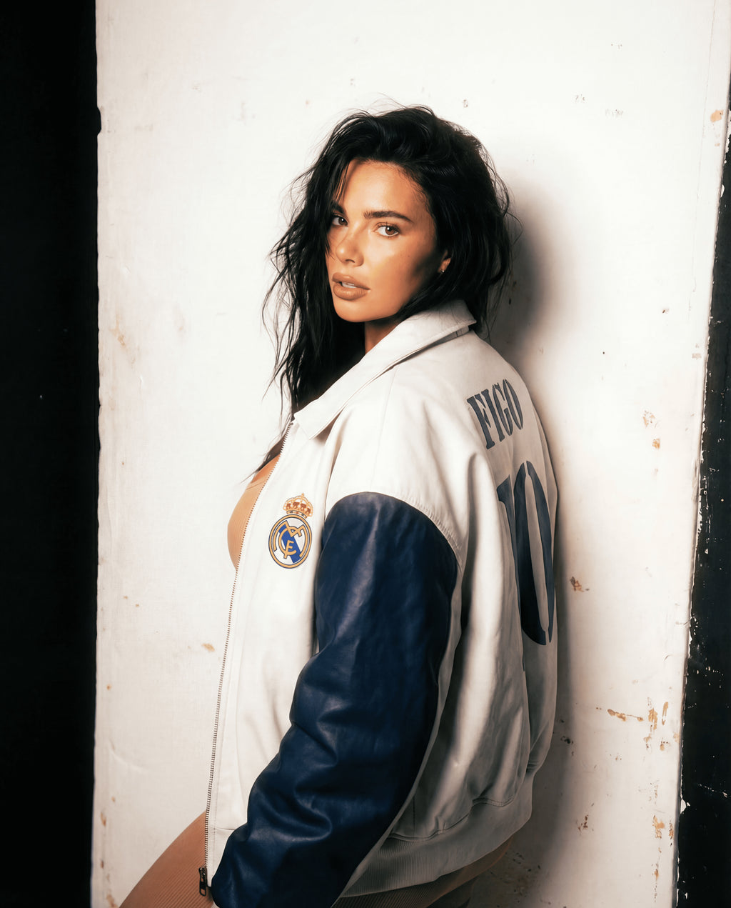 Person wearing a sports jacket with visible branding against a white wall.