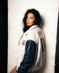 Person wearing a sports jacket with visible branding against a white wall.