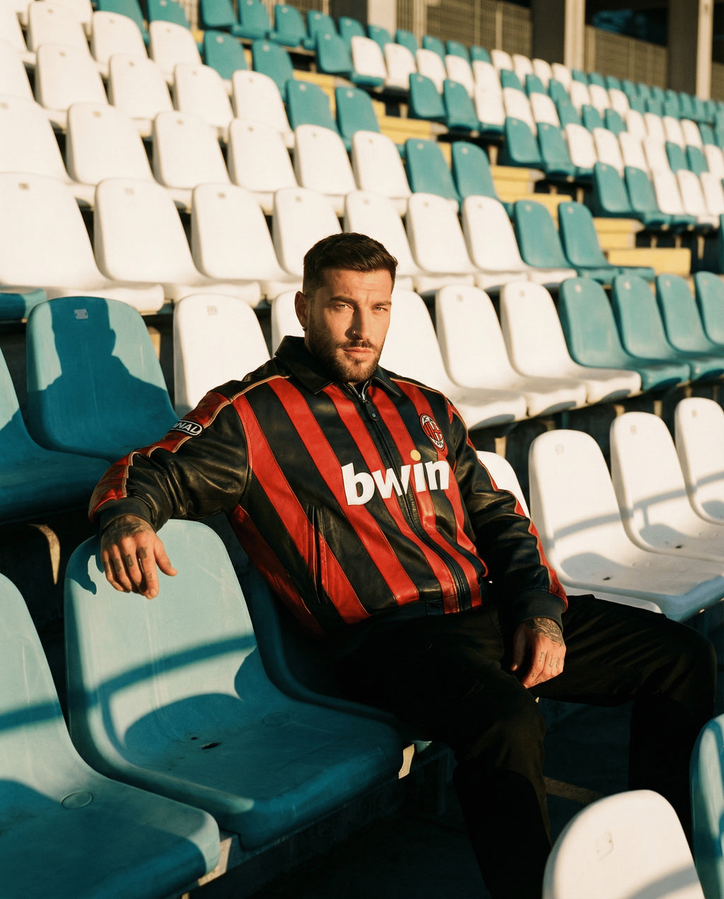 Pessoa a usar uma camisola desportiva com logótipo de marca sentada num estádio vazio.