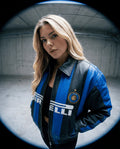Person wearing a blue and black jacket with a logo in an indoor setting